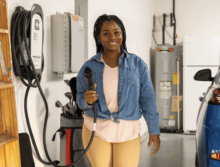 Woman holding a level 2 charger in her garage