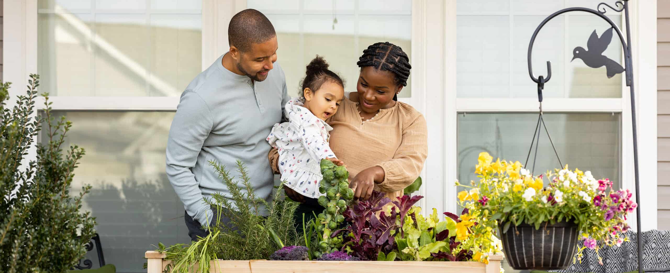 mother, father, and child together looking at their garden