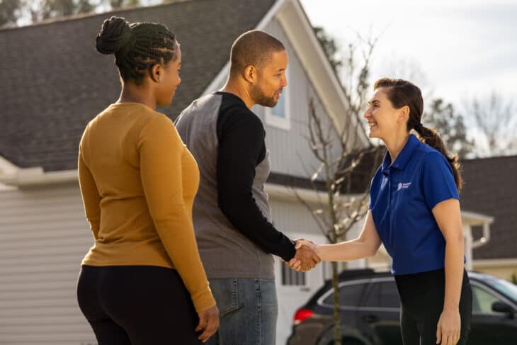 Homeowner couple taking turns shaking hands with Dominion Representative