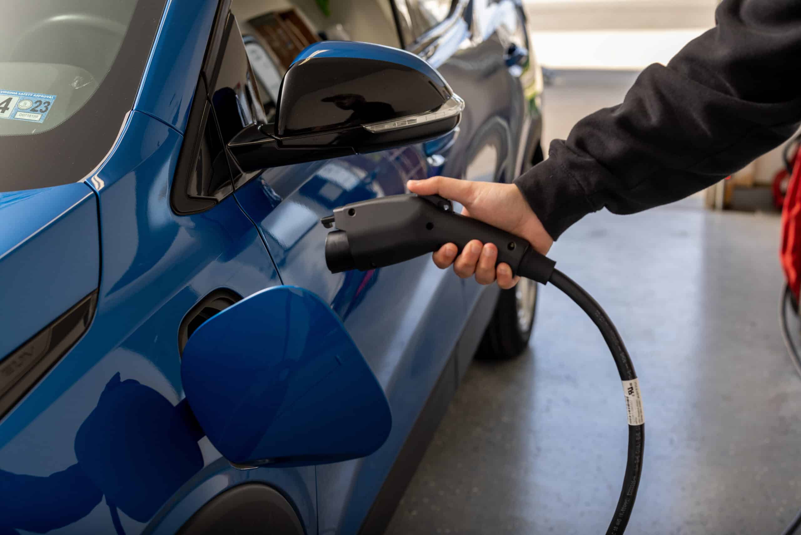 person plugging level 2 charger into an EV inside a residential garage