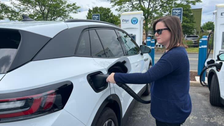 Woman using DC fast charger on EV