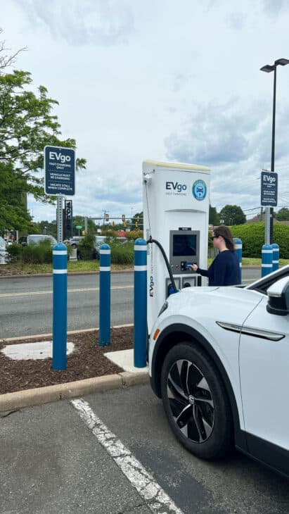 Woman charging EV at a commercial charging station