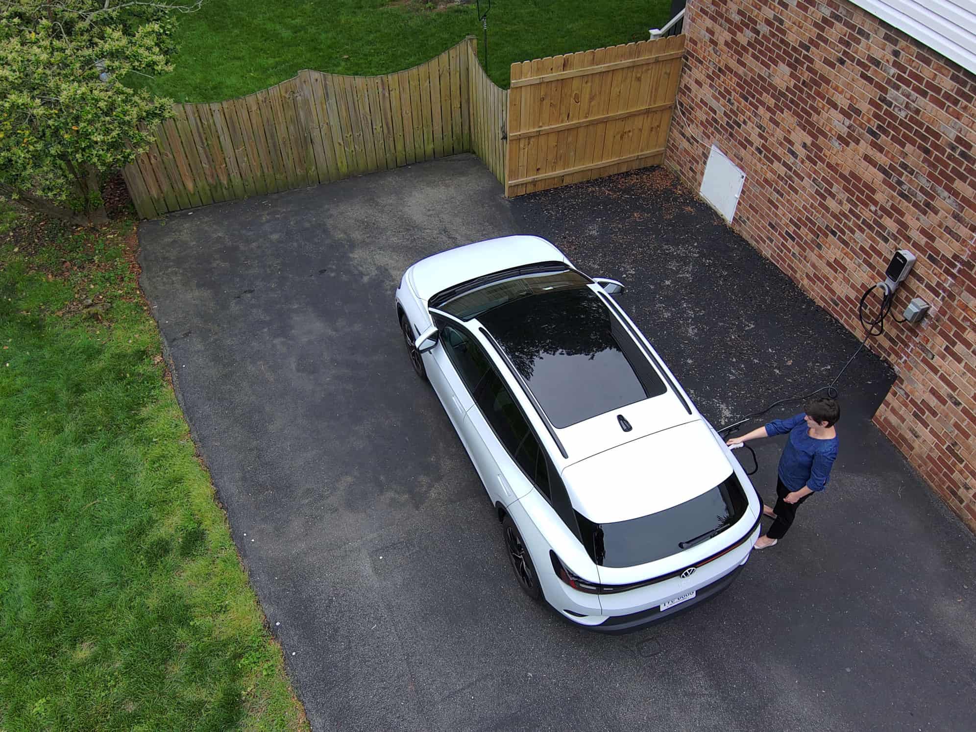 woman charging an EV in a driveway outside her home