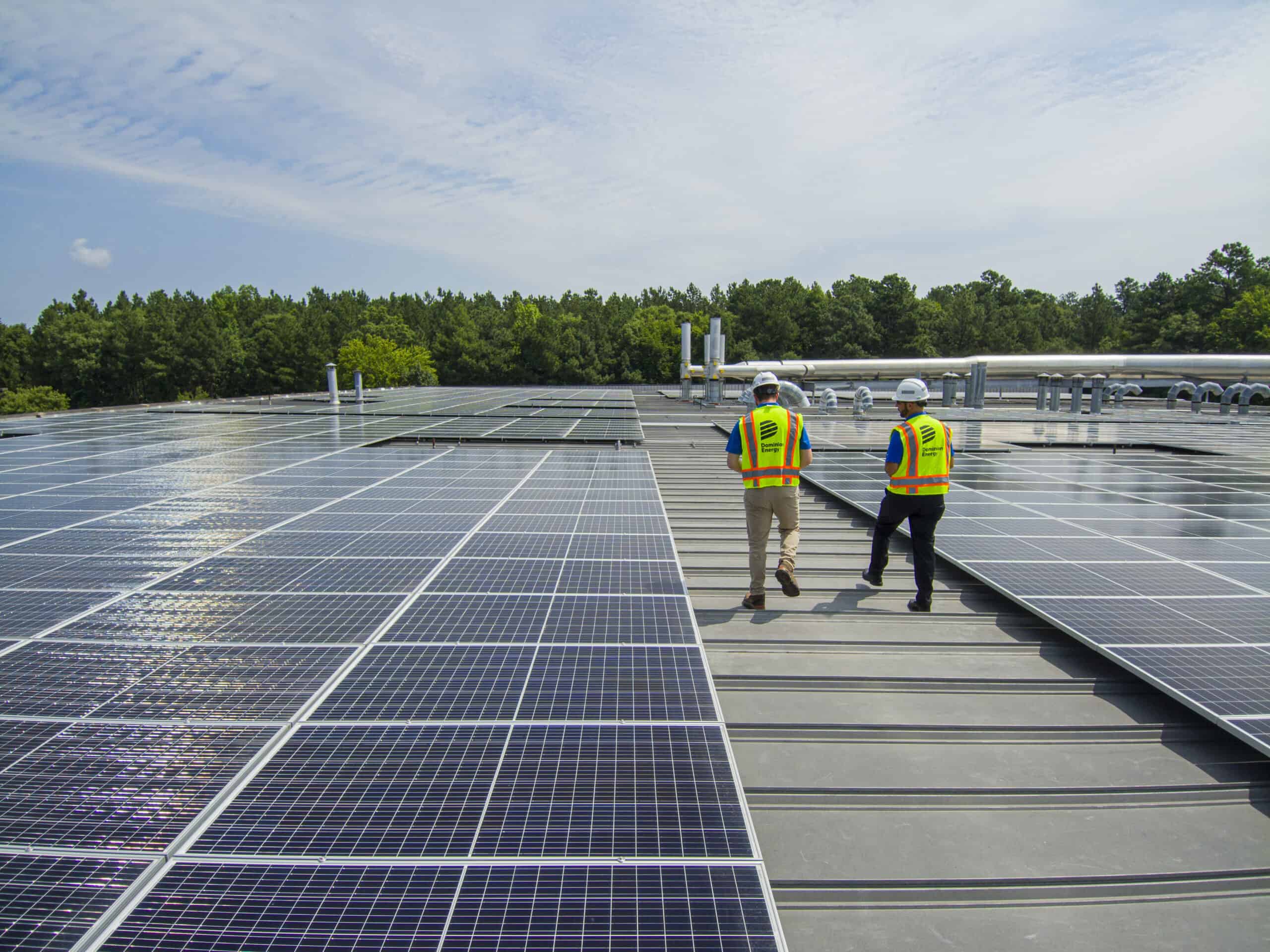 solar installers walking on a commercial roof alongside solar panels