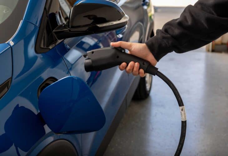 man charging electric vehicle at home